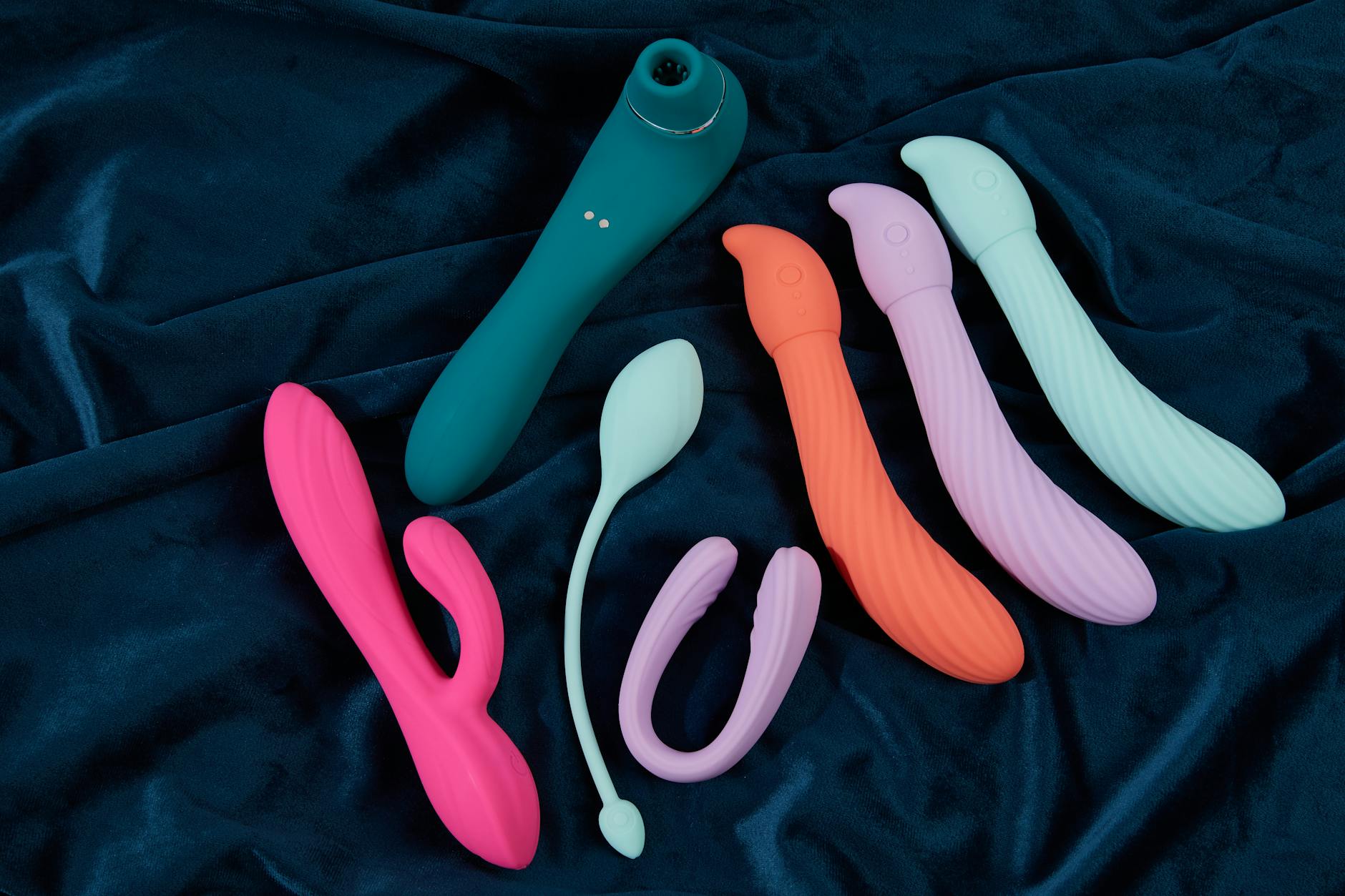 Woman holding blue and pink vibrators in a thoughtful moment, exploring pleasure options