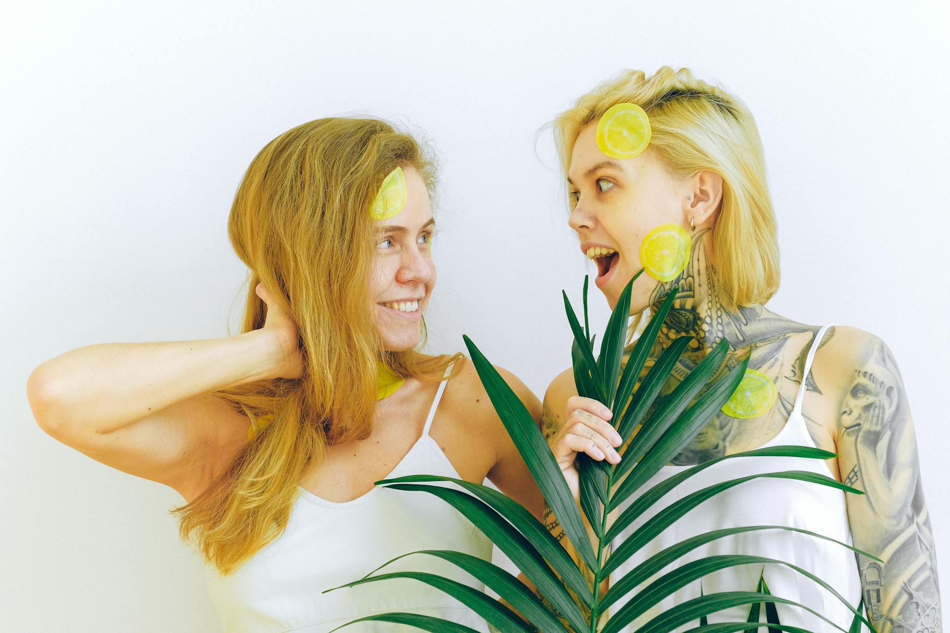 Two women smiling together with fresh lemons, representing joy and openness in intimate conversations