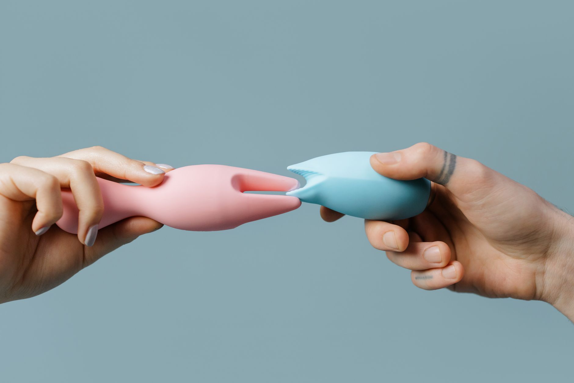 Une main tenant un vibromasseur bleu en silicone sur un fond violet uni, symbole du plaisir personnel