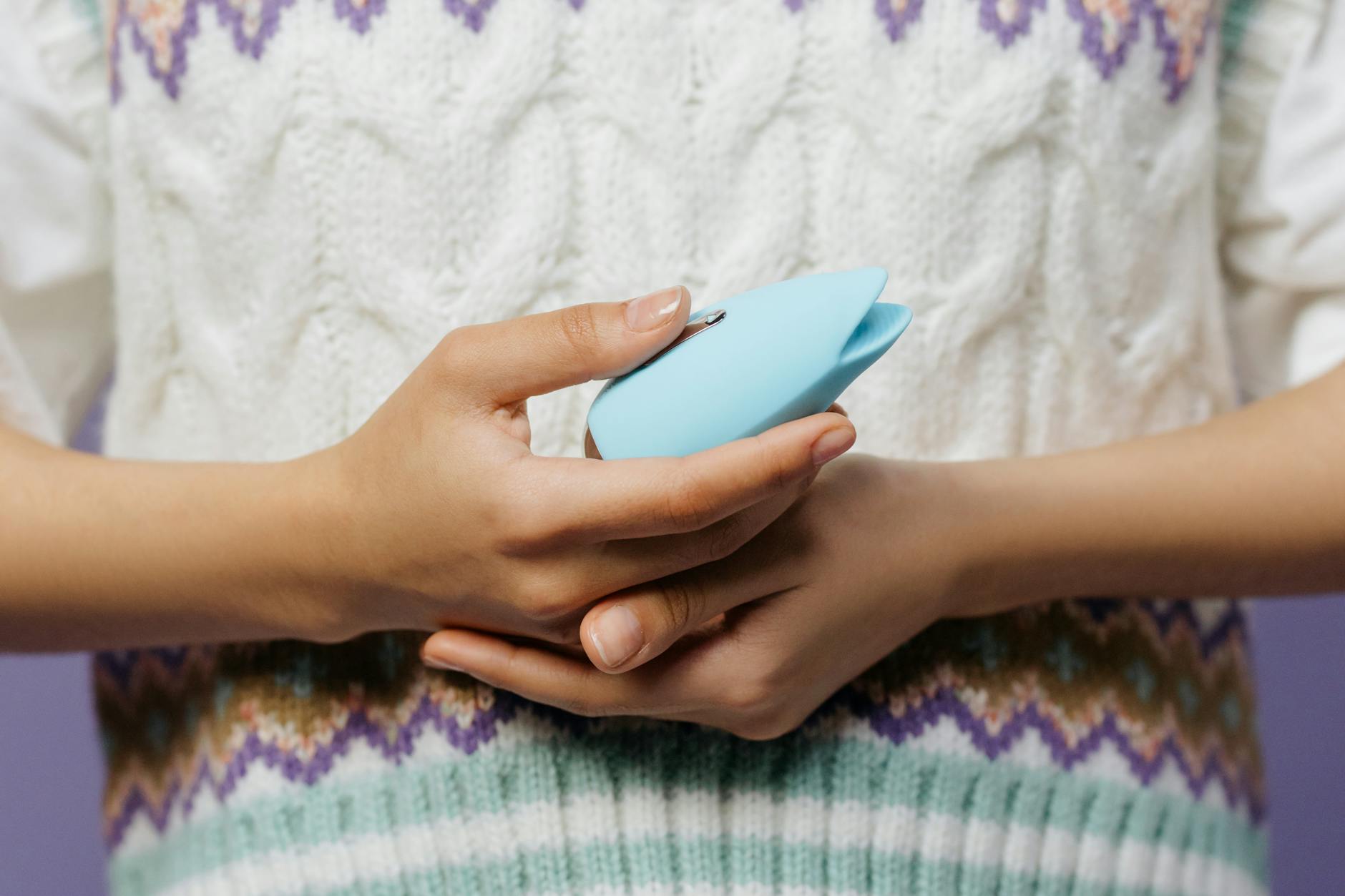 A young couple standing together indoors, holding a blue vibrator, symbolizing modern intimacy.