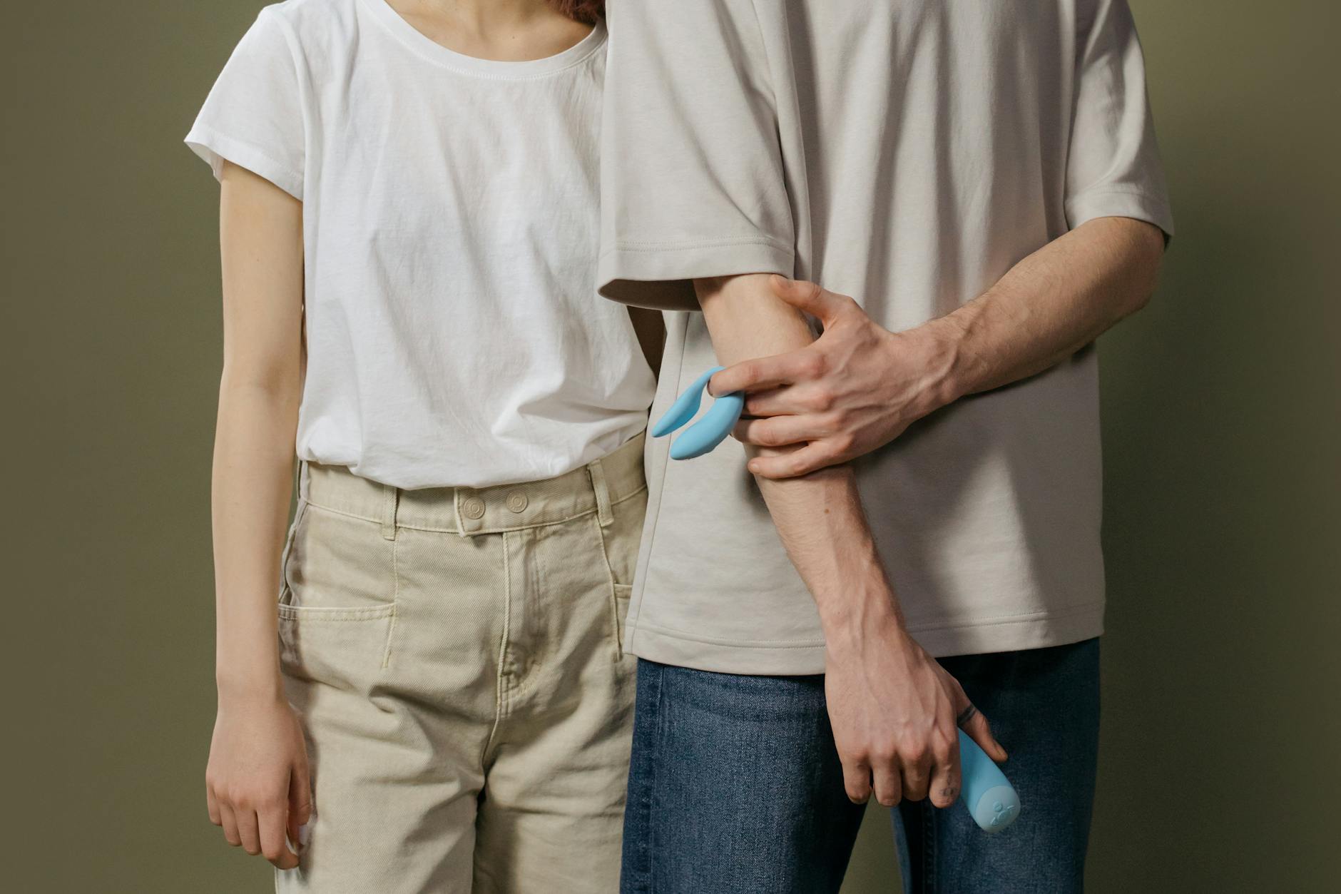 Blue silicone clitoral vibrator held in hand against purple background