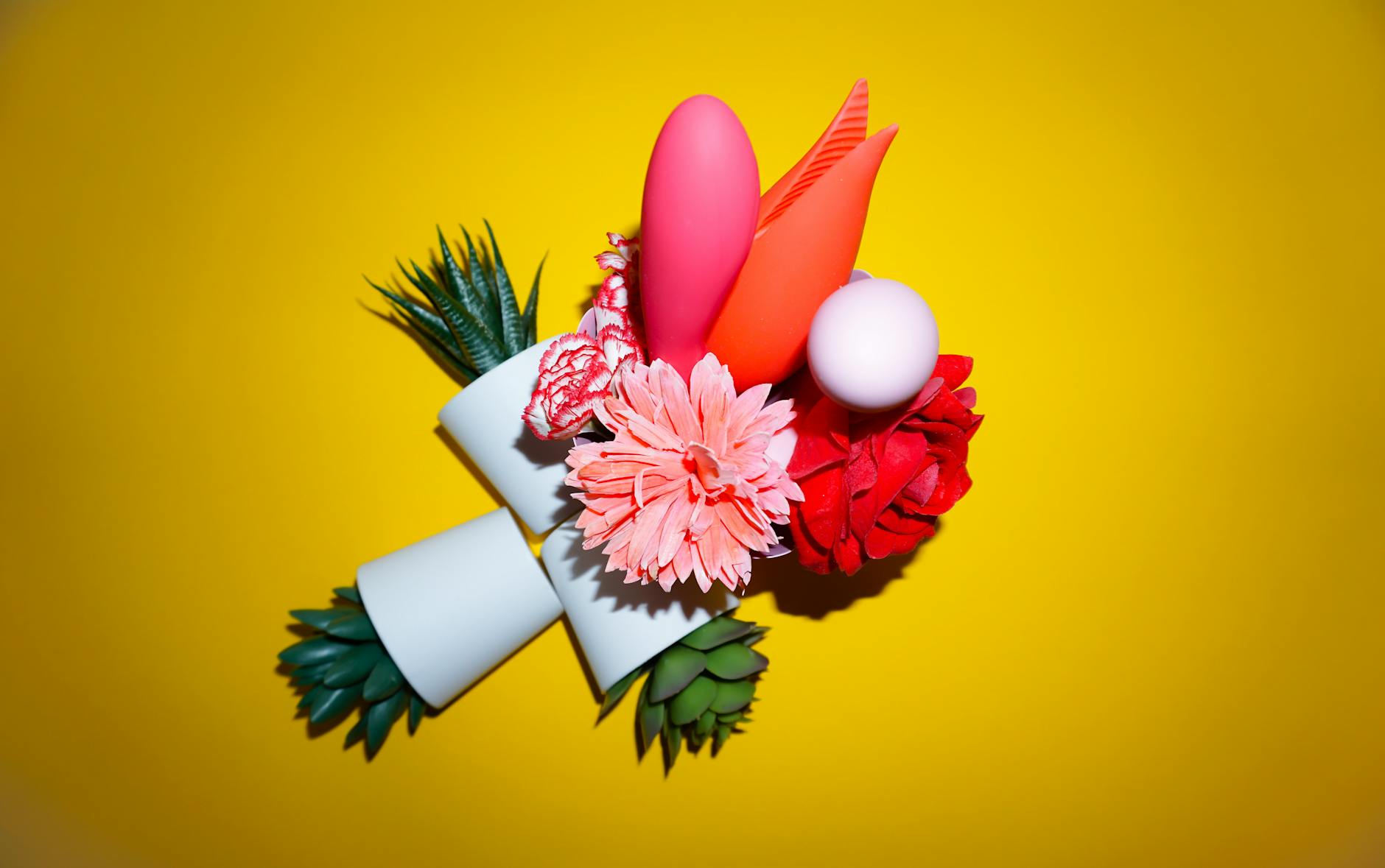 Colorful clitoral vibrators and lemon-shaped adult toys arranged on a bright yellow surface