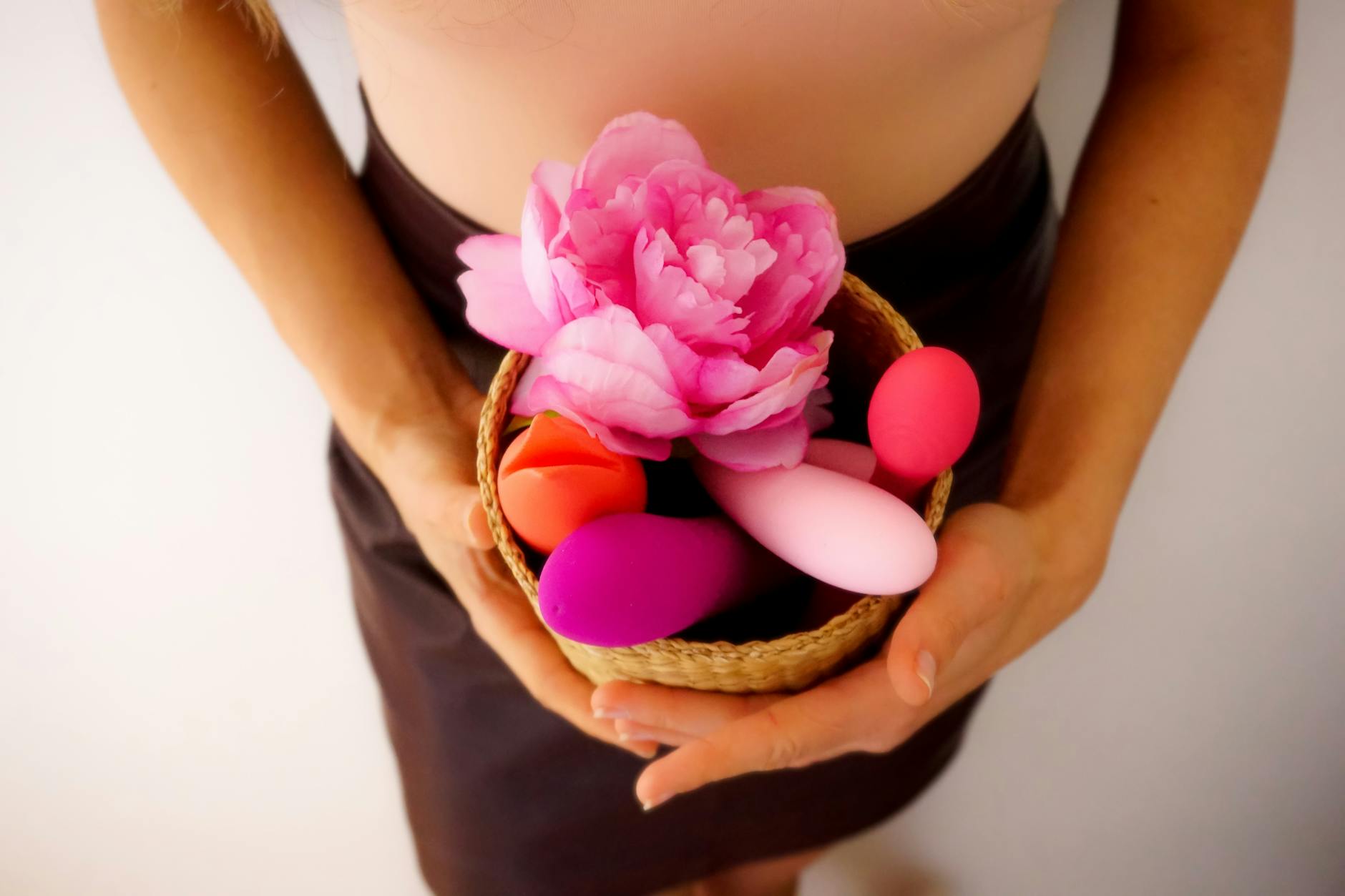 A collection of colorful vibrators and lemon vibrators in a basket with a pink flower